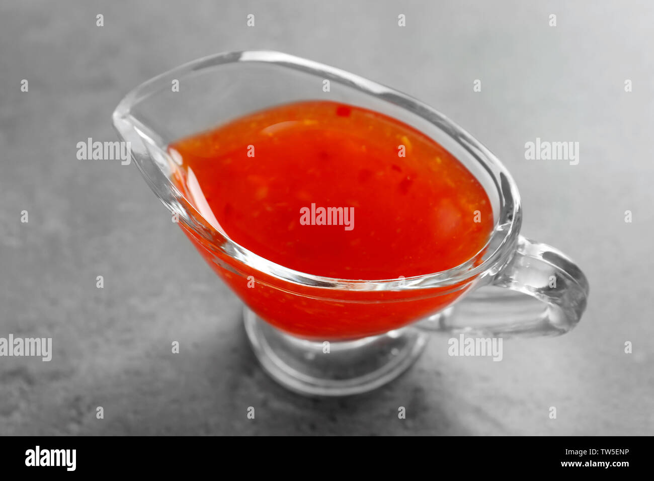Chili sauce in gravy boat on table Stock Photo
