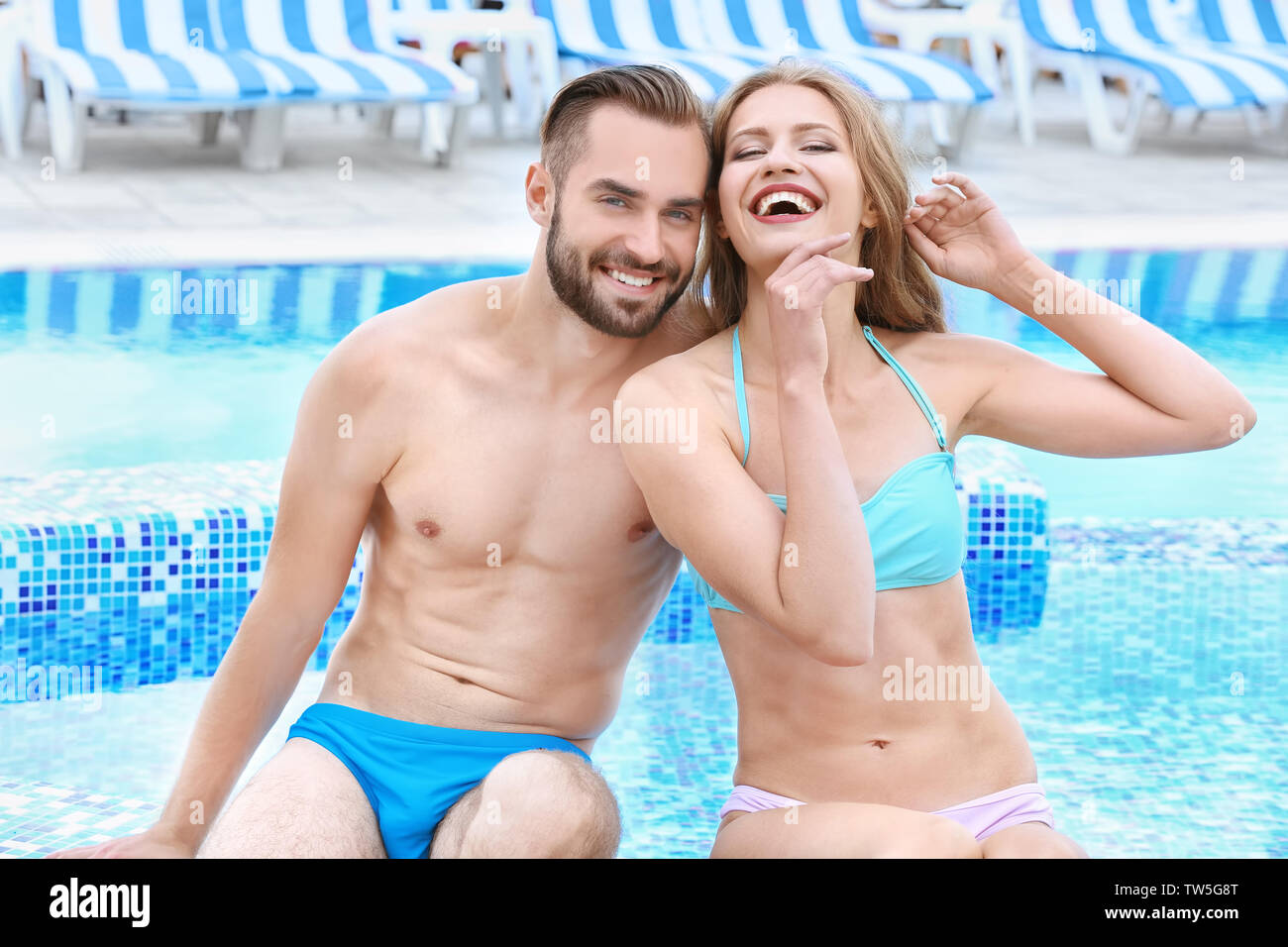 Happy young couple sitting near swimming pool Stock Photo - Alamy