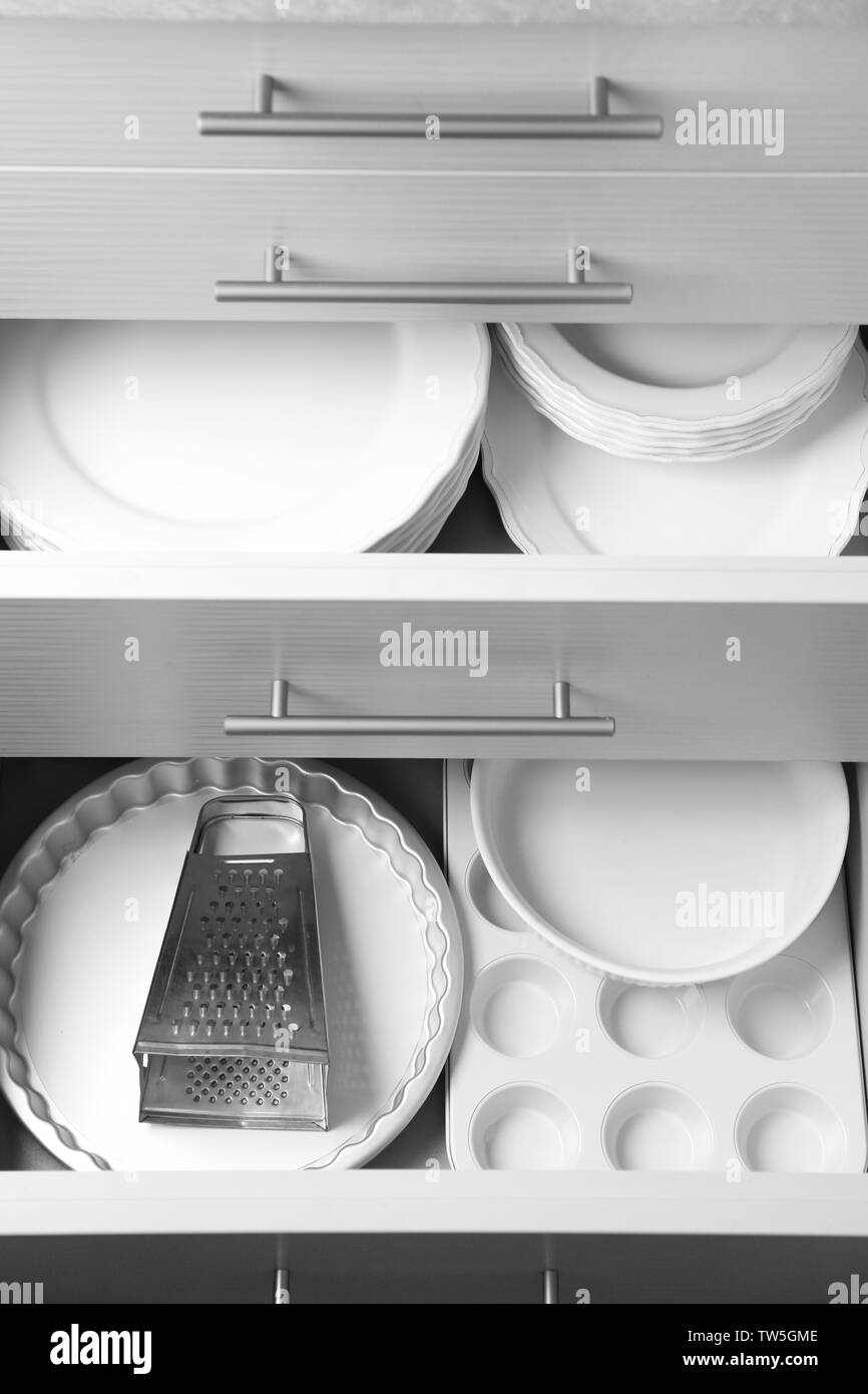Set of kitchenware and ceramic plates in kitchen drawers Stock Photo