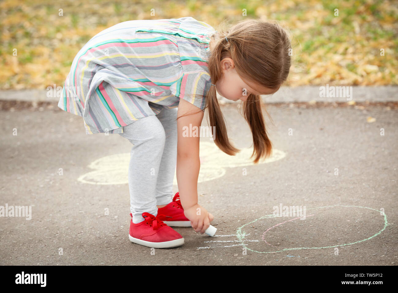 Cute little girl drawing with chalk on asphalt Stock Photo - Alamy