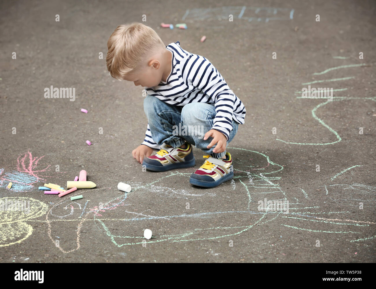 Cute little boy drawing with chalk on asphalt Stock Photo - Alamy