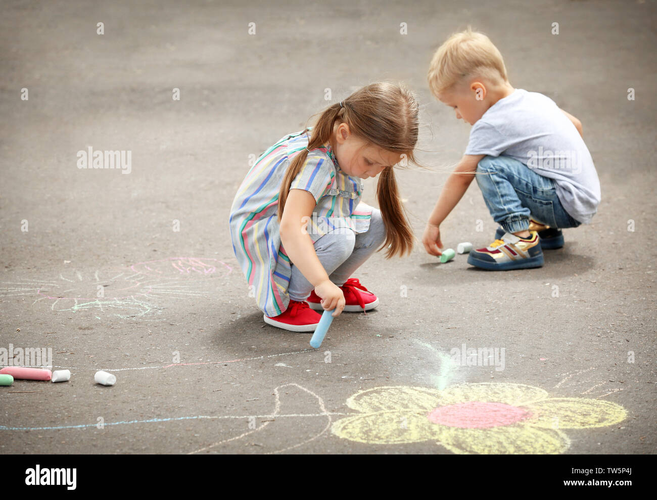 Cute little children drawing with chalk on asphalt Stock Photo - Alamy