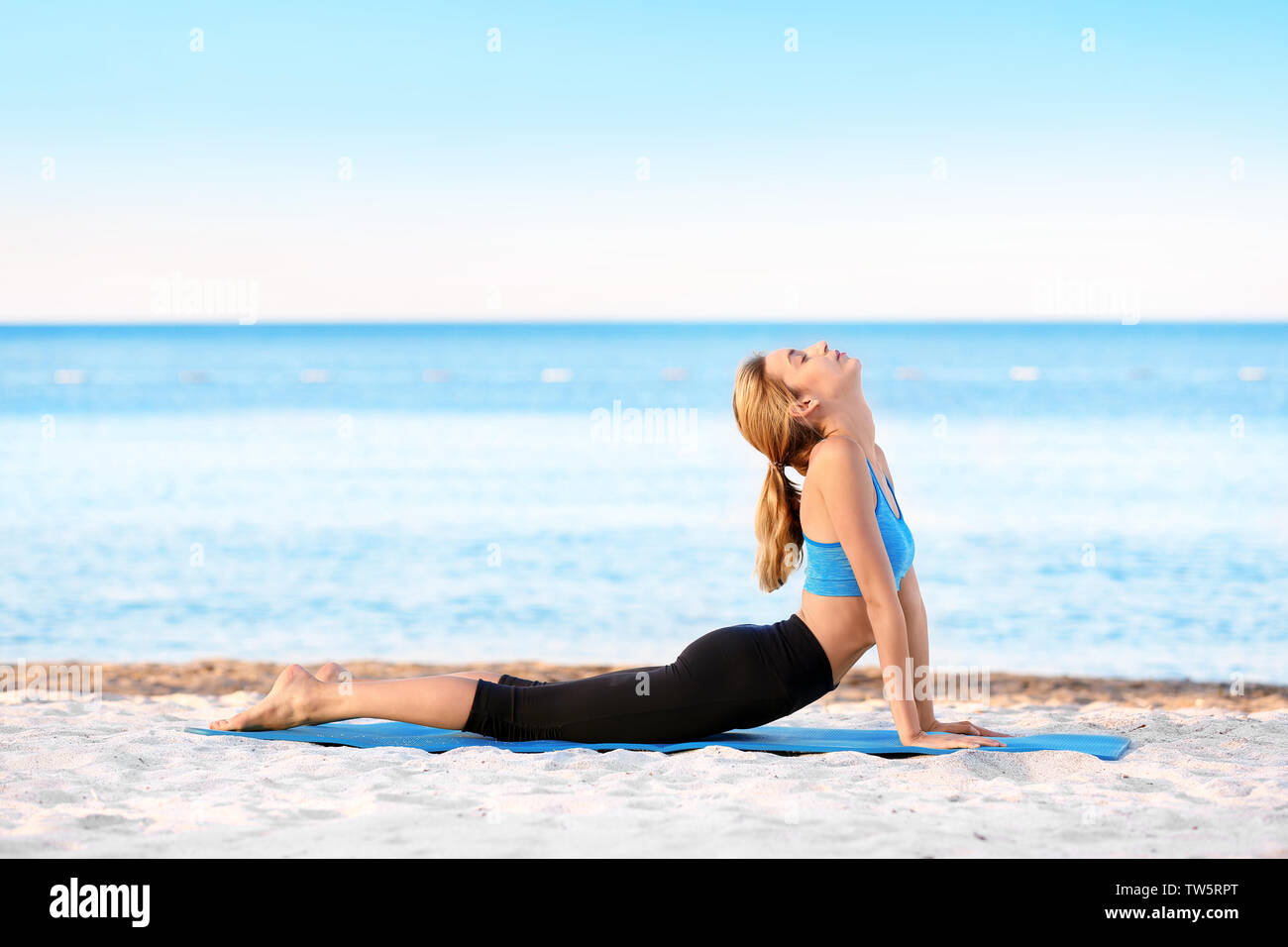 Beautiful young woman practicing yoga on sea beach Stock Photo - Alamy