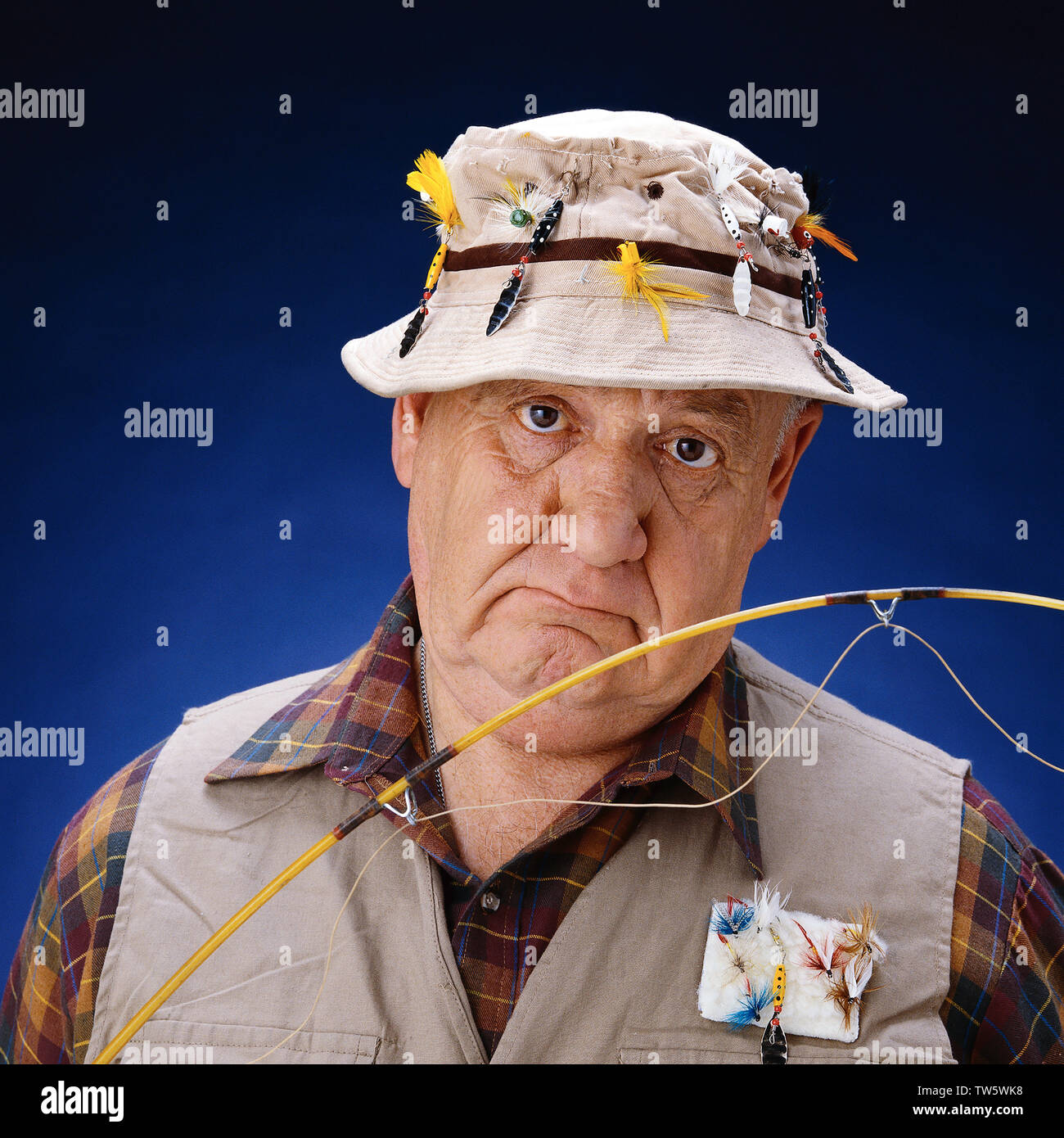 Old fisherman with pole Wearing a hat full of Tackle looking very silly  Stock Photo - Alamy