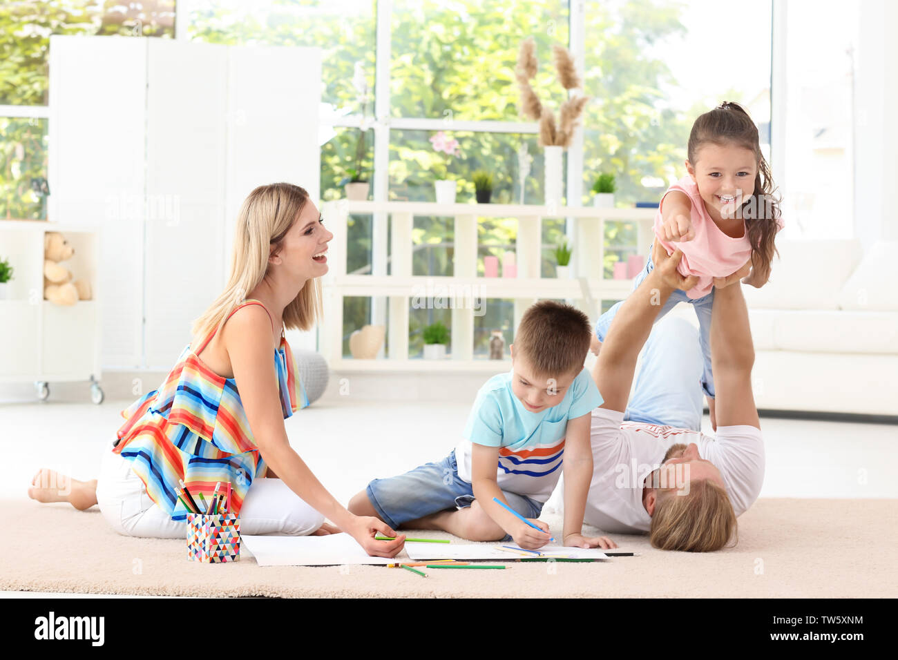 Happy couple spending time with children at home Stock Photo