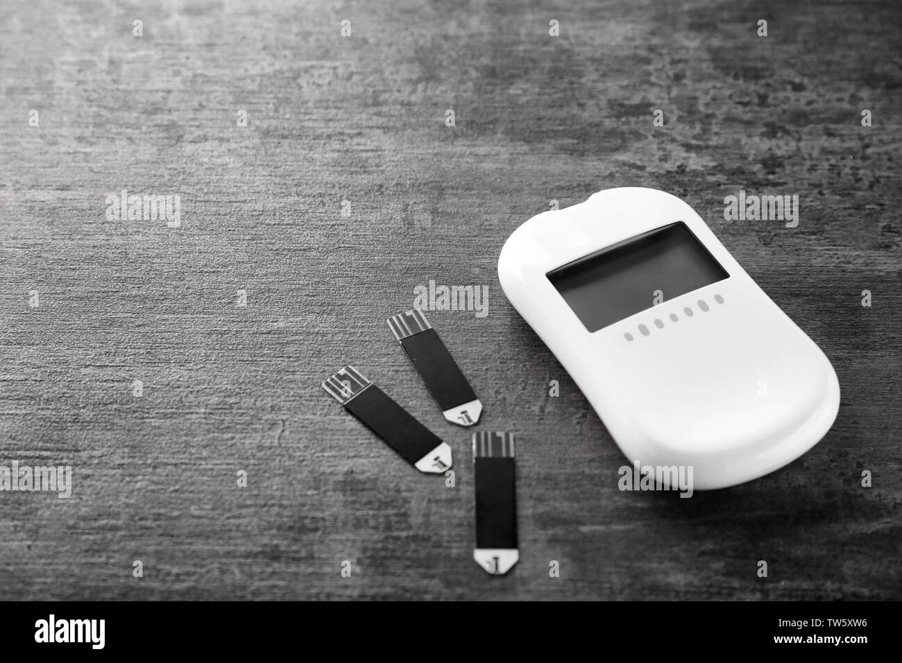 Digital glucose meter and test strips on table Stock Photo