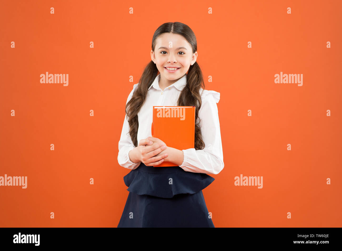 back to school. happy child. reading lesson. Book store concept. small girl in school uniform. schoolgirl writing notes on orange background. get information form book. Study and education. education. Stock Photo