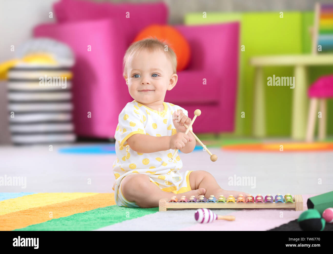 Cute little baby playing with musical instrument at home Stock Photo