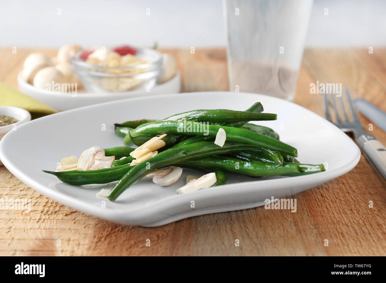 Plate with delicious green beans, almond and mushrooms on table Stock Photo
