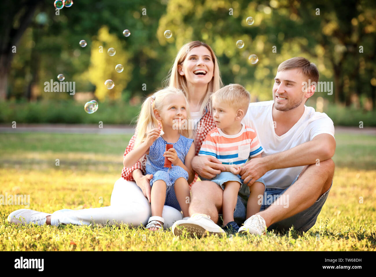 Happy family blowing soap bubbles in park on sunny day Stock Photo - Alamy