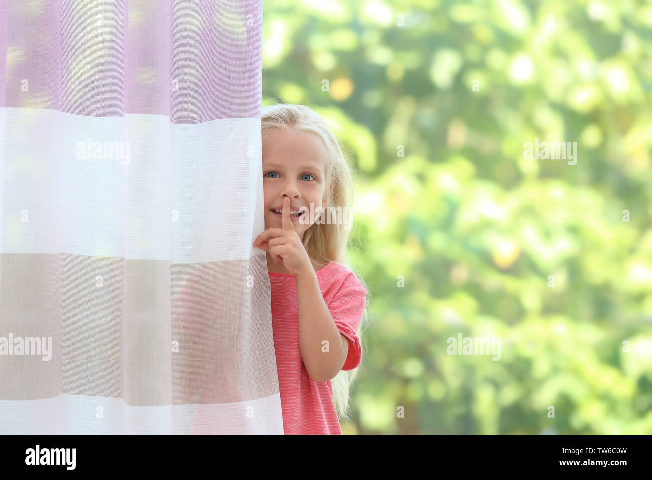 Cute little girl hiding behind curtain at home Stock Photo Alamy