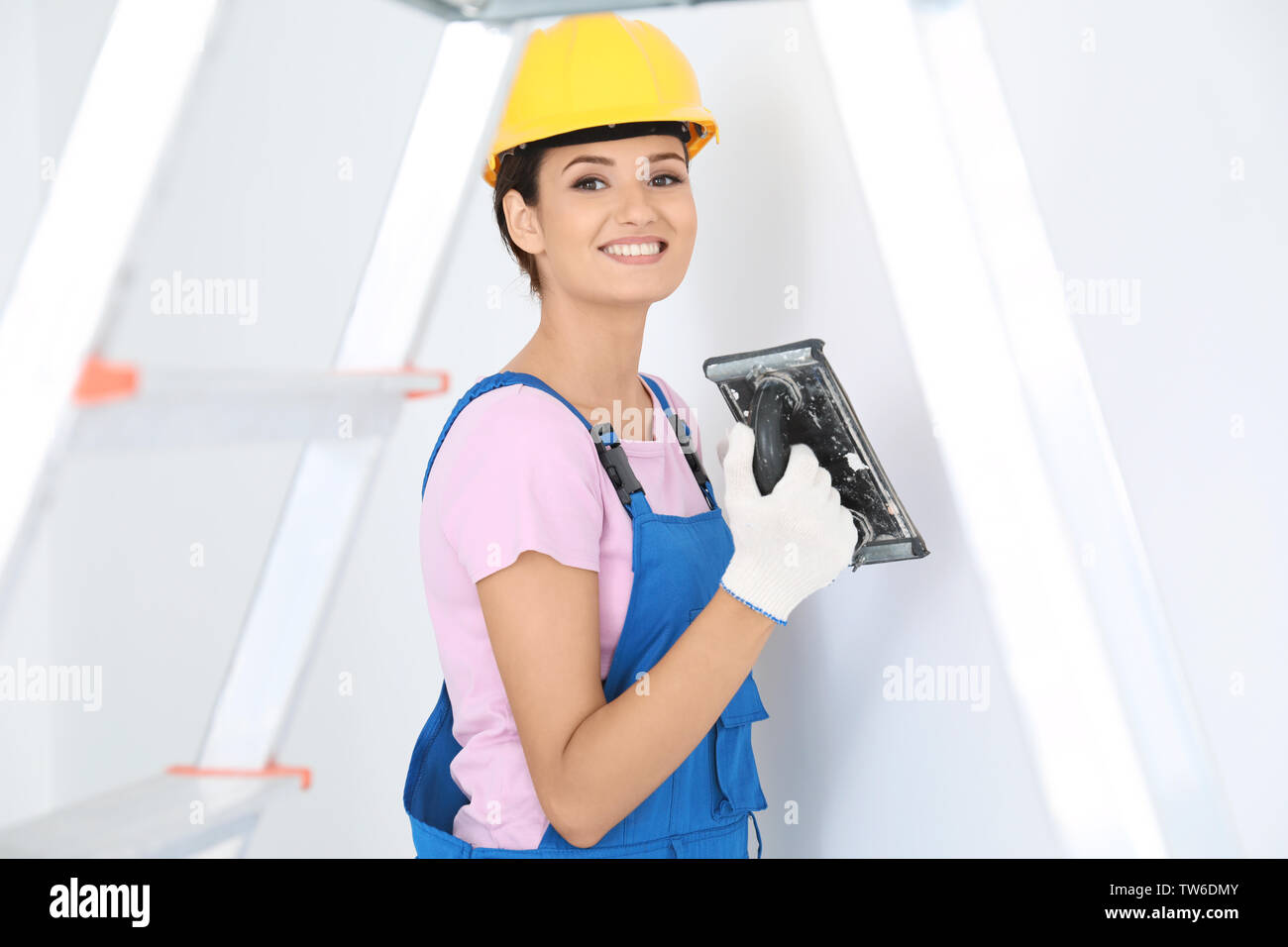 Young female decorator working with plastering trowel indoors Stock Photo