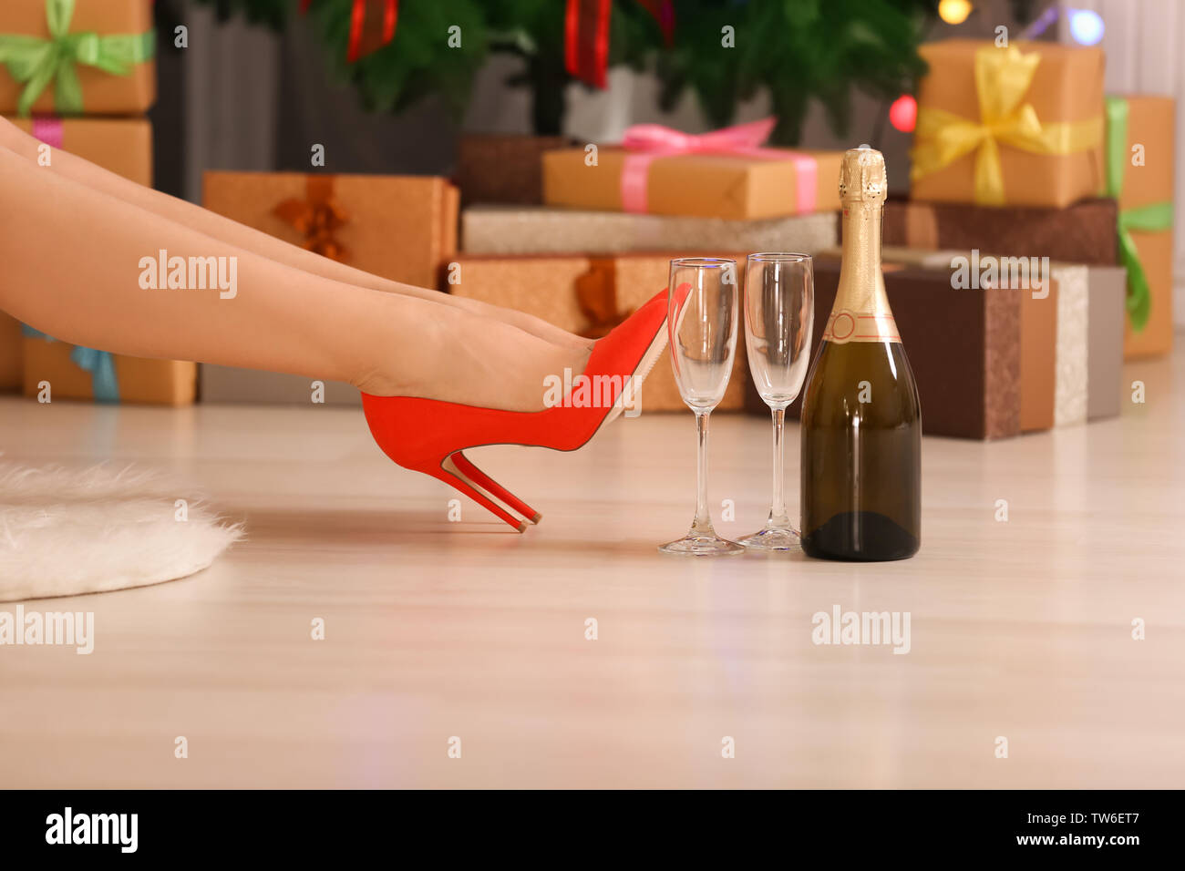 Woman in high heel shoes, glasses and bottle of champagne at home Stock Photo