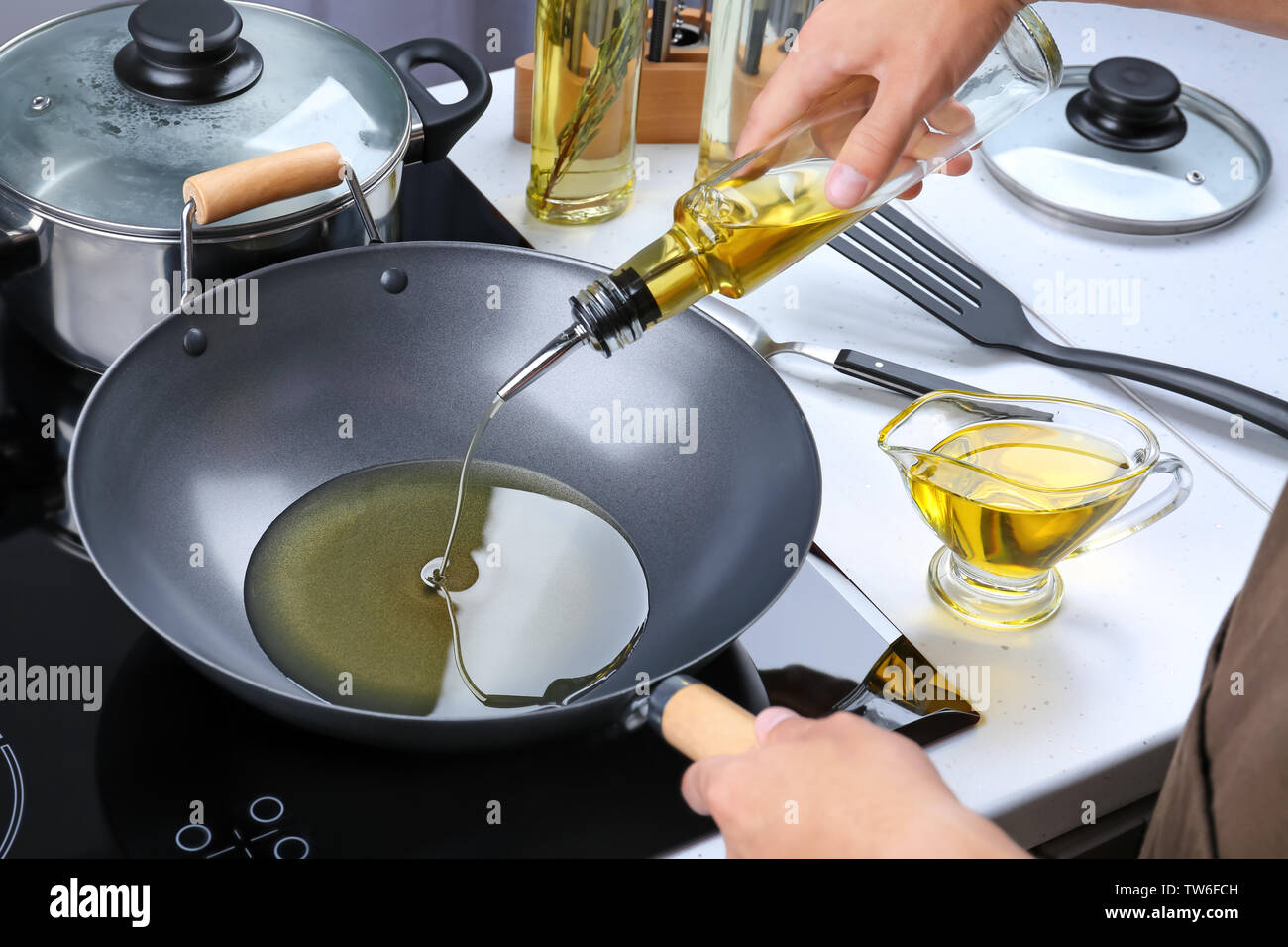 Man pouring cooking oil from bottle into frying pan on stove Stock Photo -  Alamy