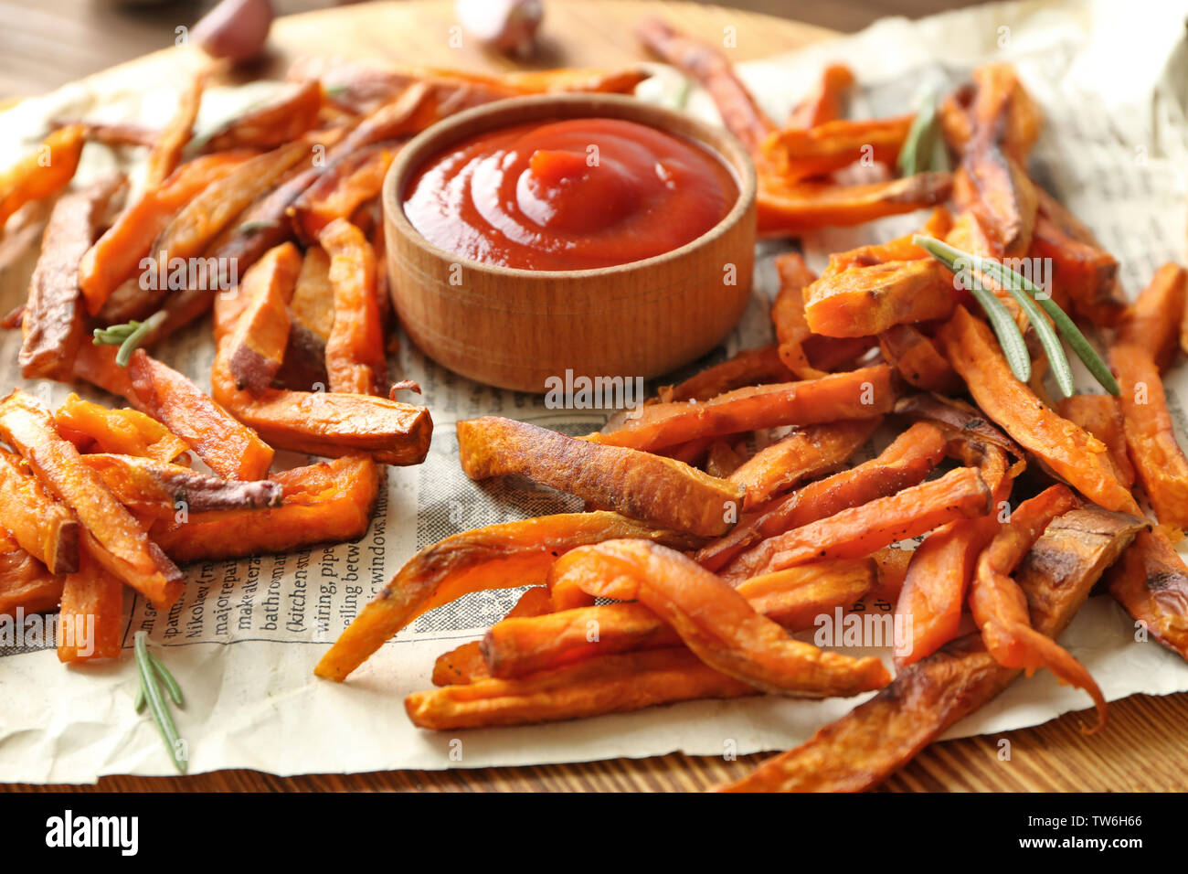 Deep fried sweet potato sticks with sauce on paper, closeup Stock Photo