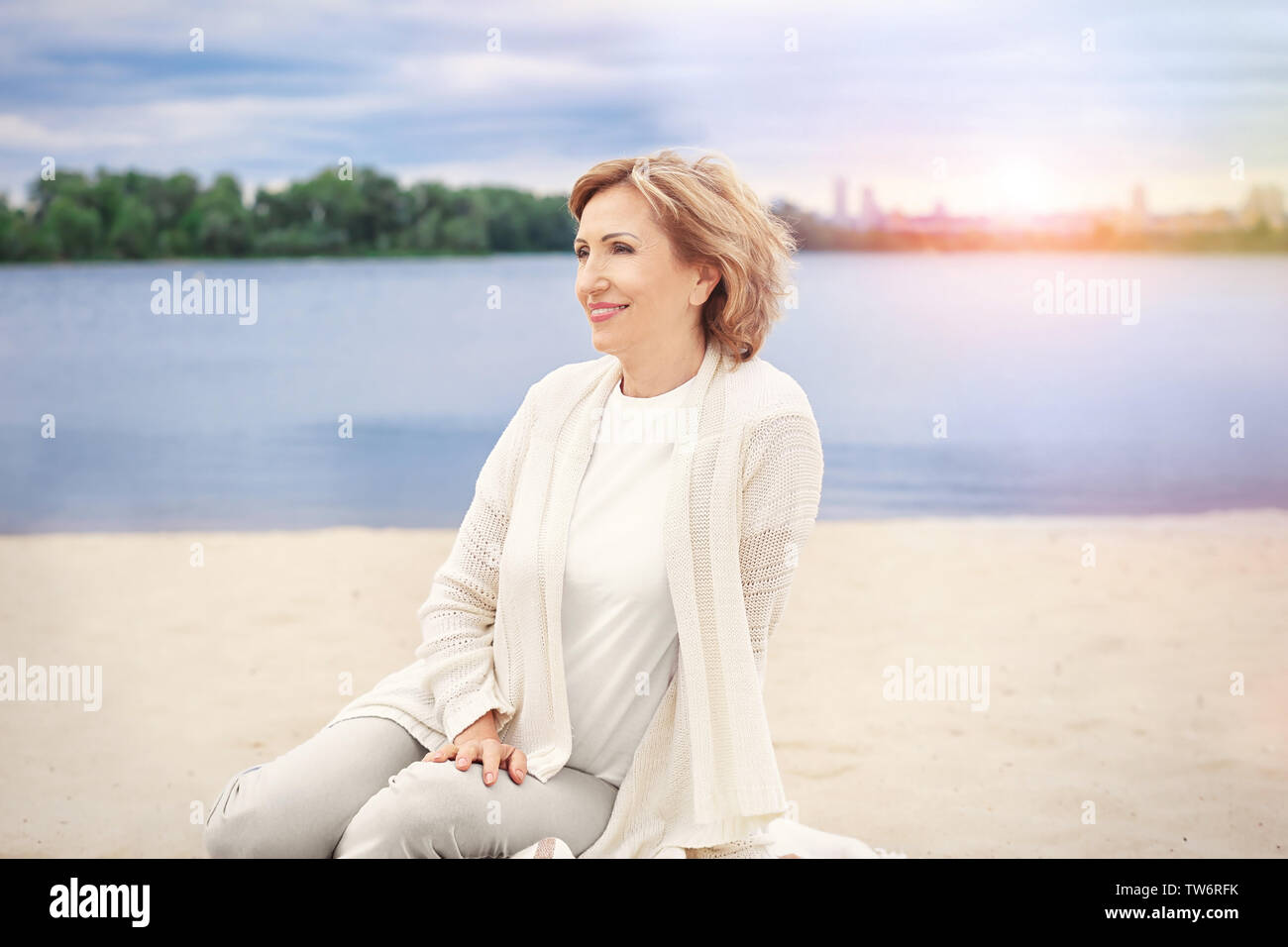 Elderly woman relaxing on beach Stock Photo - Alamy