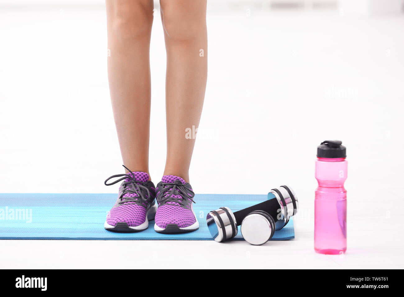 Sporty young woman standing on mat in gym Stock Photo - Alamy