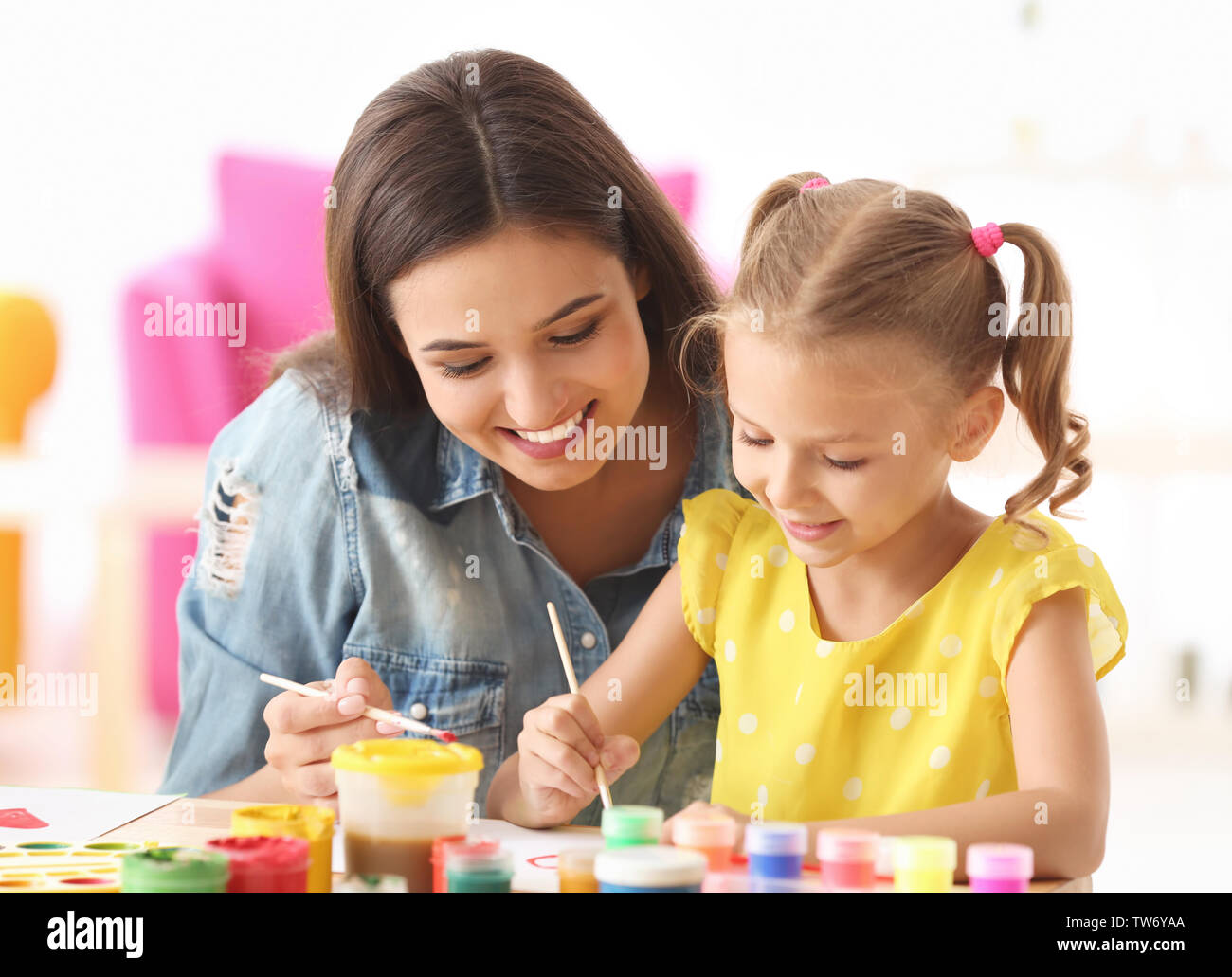 Cute girl with mother painting at table indoors Stock Photo - Alamy