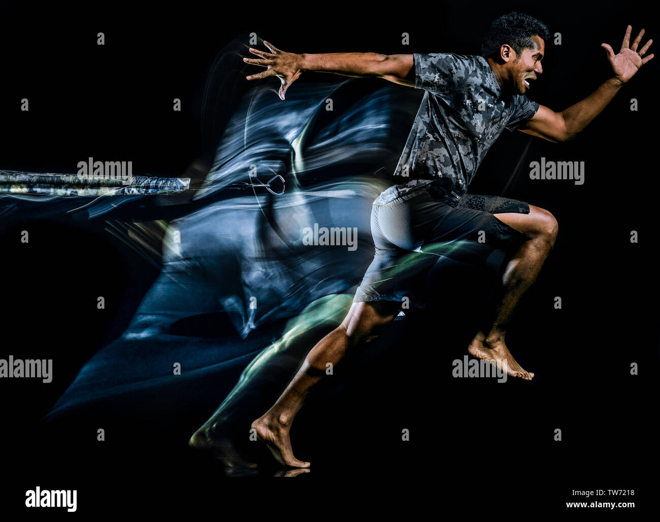 one afro american man exercising boot camp fitness trx exercises isolated on black background with light painting speed effect Stock Photo