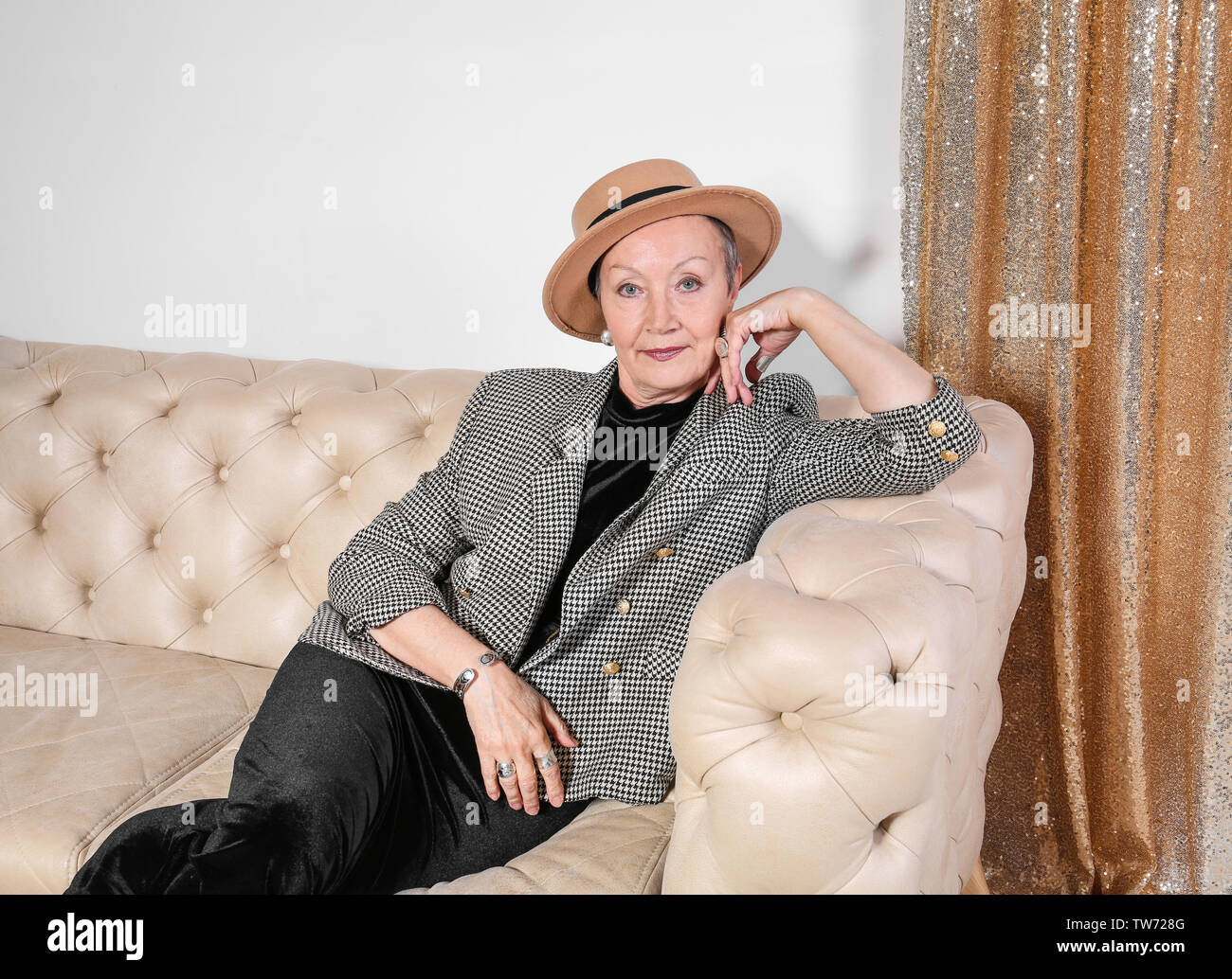 Attractive mature woman sitting on sofa at home Stock Photo - Alamy