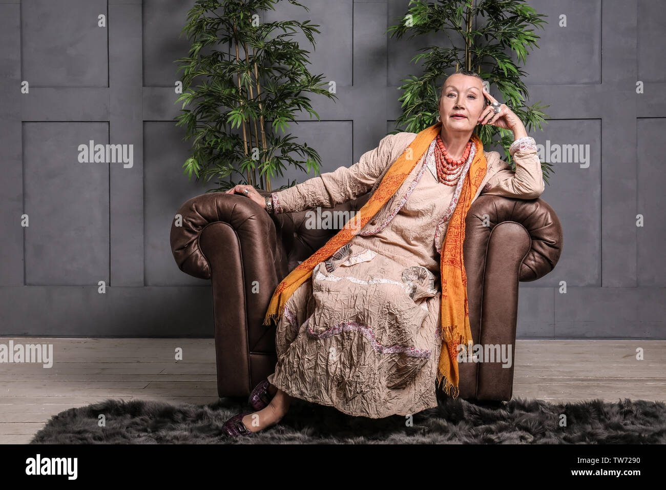 Attractive mature woman sitting in armchair at home Stock Photo - Alamy