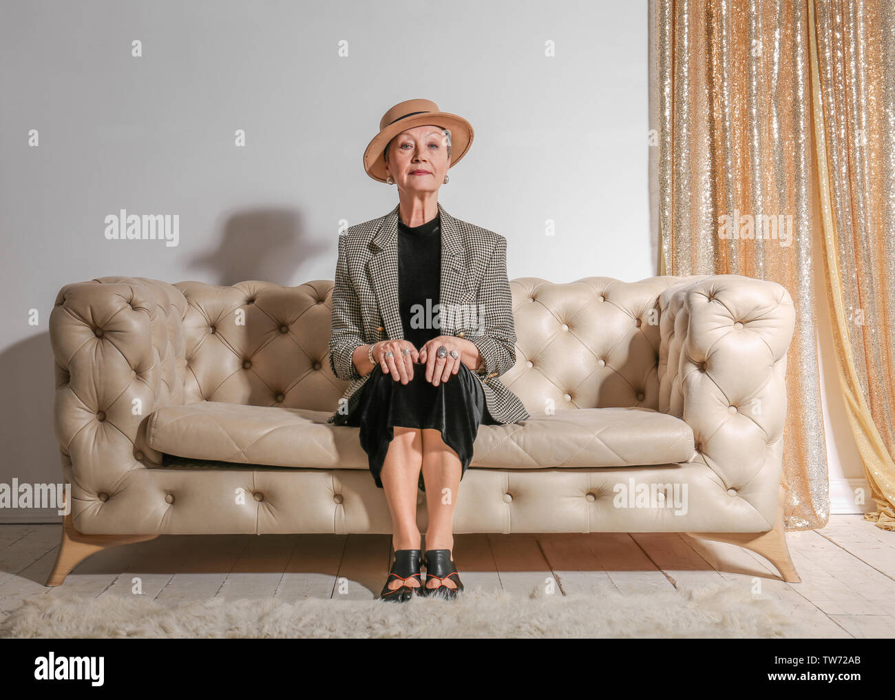 Attractive mature woman sitting on sofa at home Stock Photo - Alamy