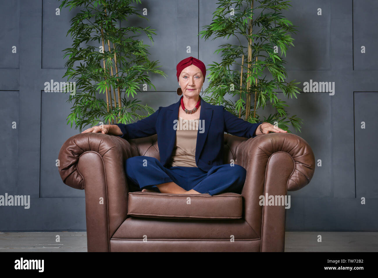 Attractive mature woman sitting in armchair at home Stock Photo - Alamy