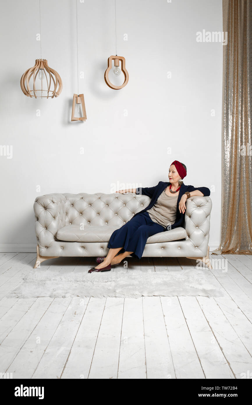 Attractive mature woman sitting on sofa at home Stock Photo - Alamy
