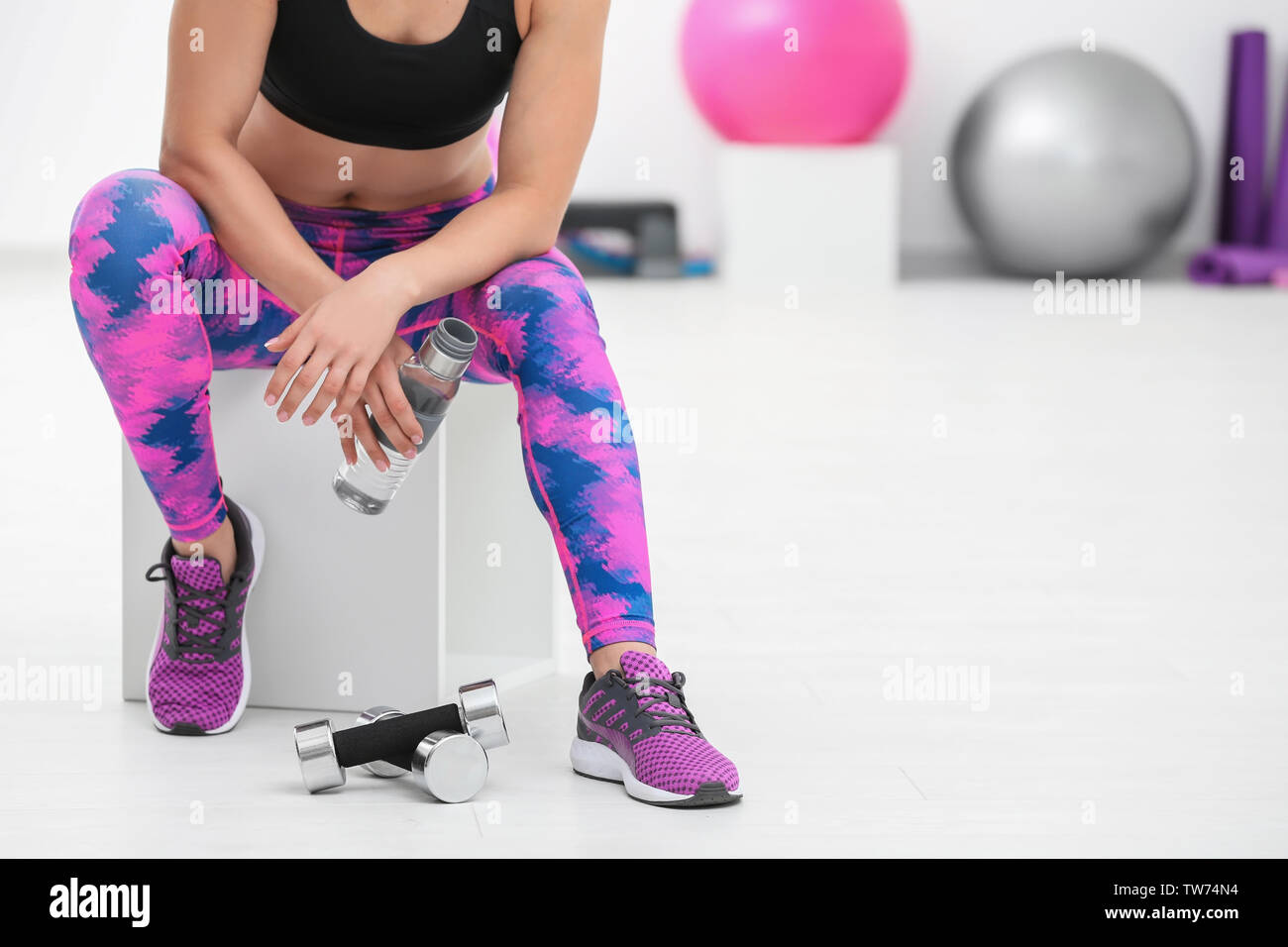 Sporty young woman with bottle of water in gym Stock Photo - Alamy