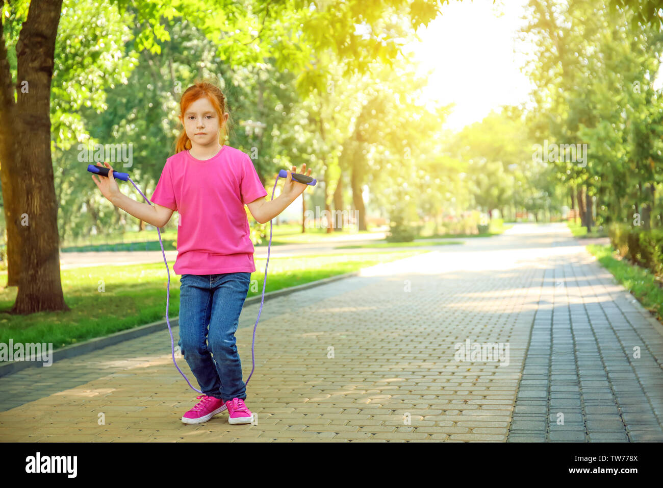 Cute little girl jumping rope in park Stock Photo - Alamy