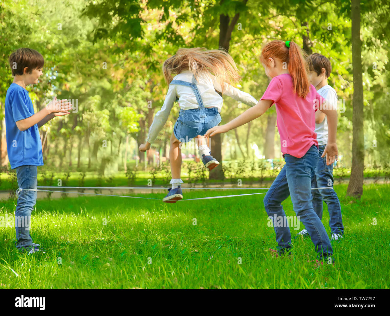 Cute little children jumping rope in park Stock Photo - Alamy