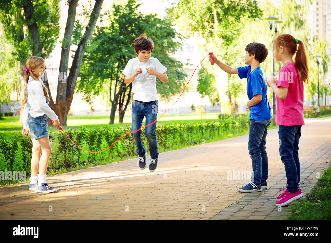 Cute little children jumping rope in park Stock Photo - Alamy