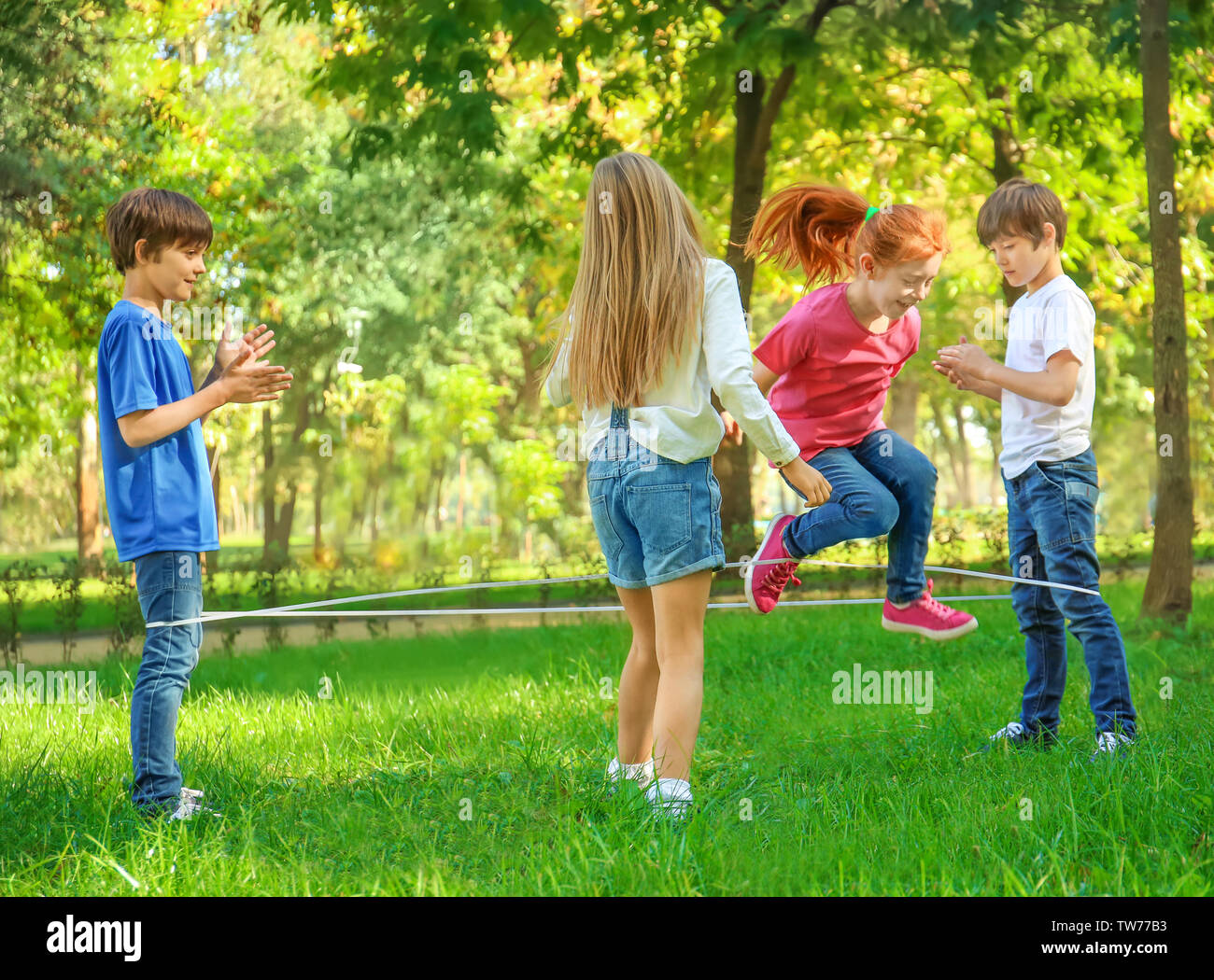 Cute little children jumping rope in park Stock Photo - Alamy