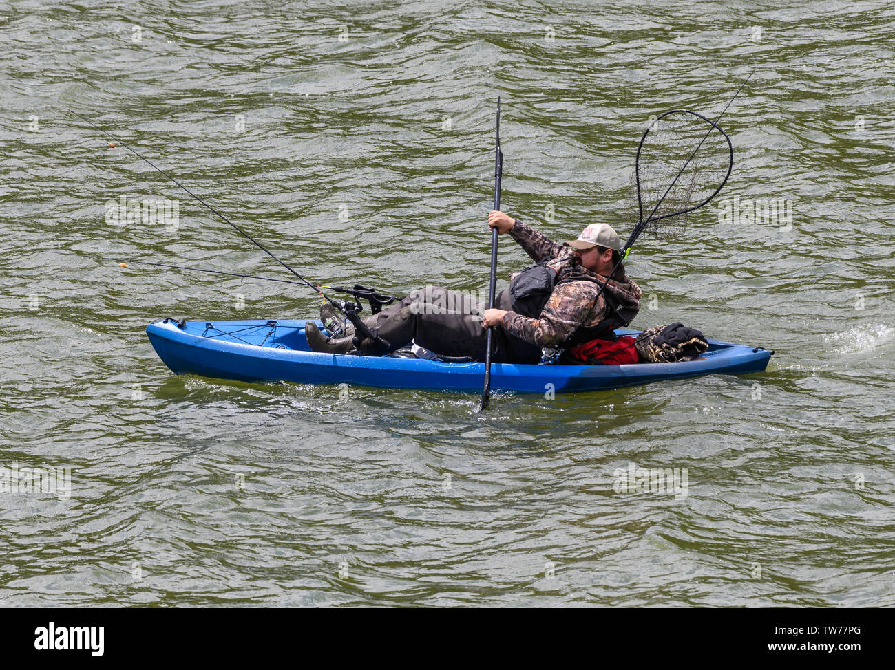 A man paddling and fishing in a kayak on a lake . Del Valle Regional
