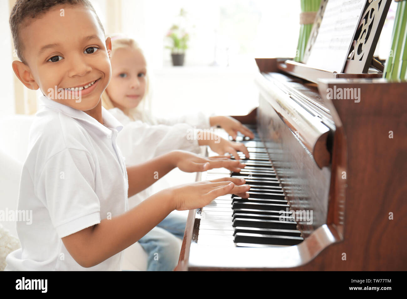 African-American boy with little girl playing piano indoors Stock Photo ...