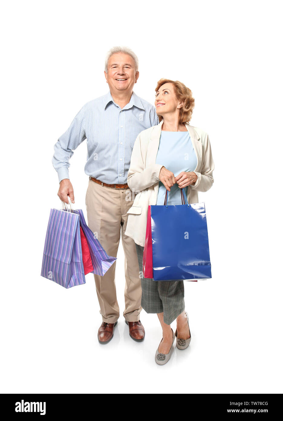 Elderly couple holding shopping bags on white background Stock Photo