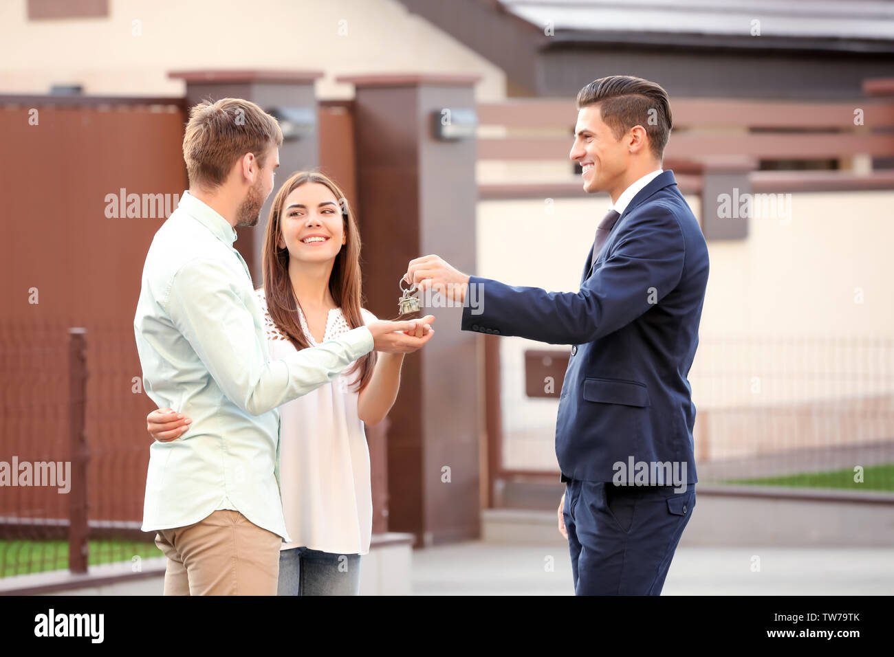 Real estate agent giving key to young couple near house Stock Photo - Alamy