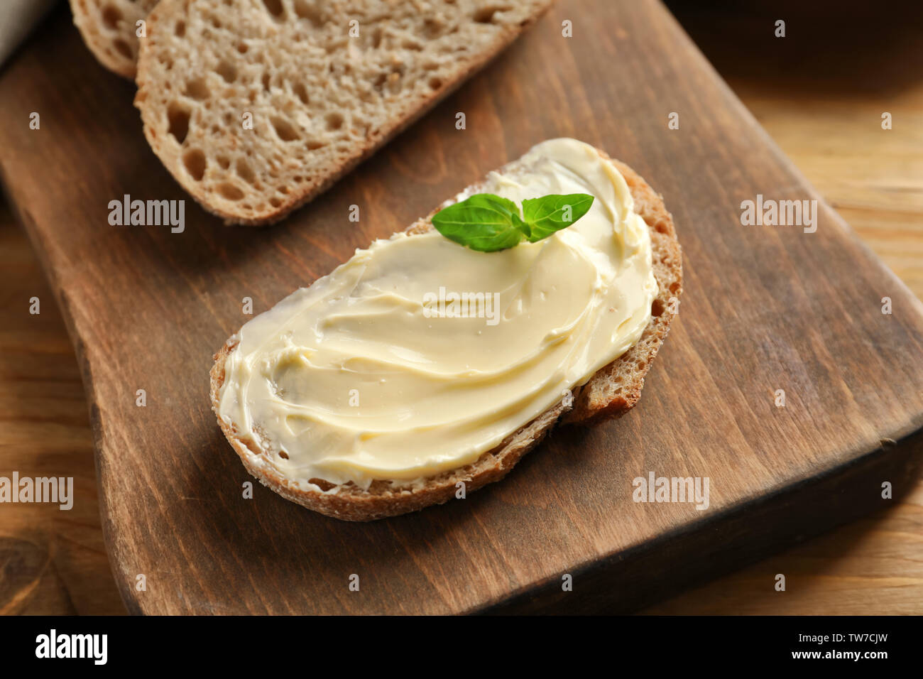 Slice of bread with butter on wooden board Stock Photo - Alamy