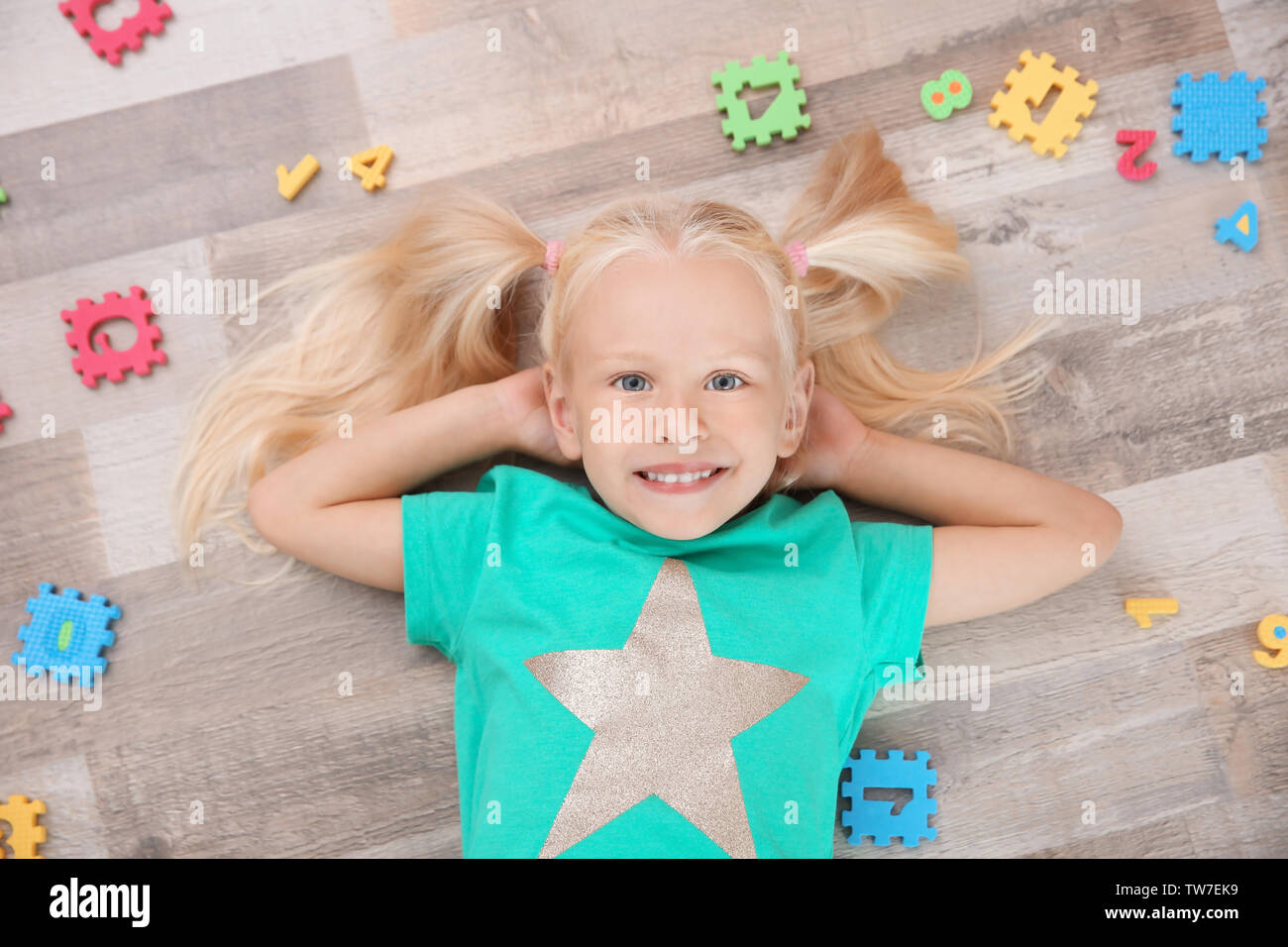Cute little girl lying on floor at home Stock Photo - Alamy