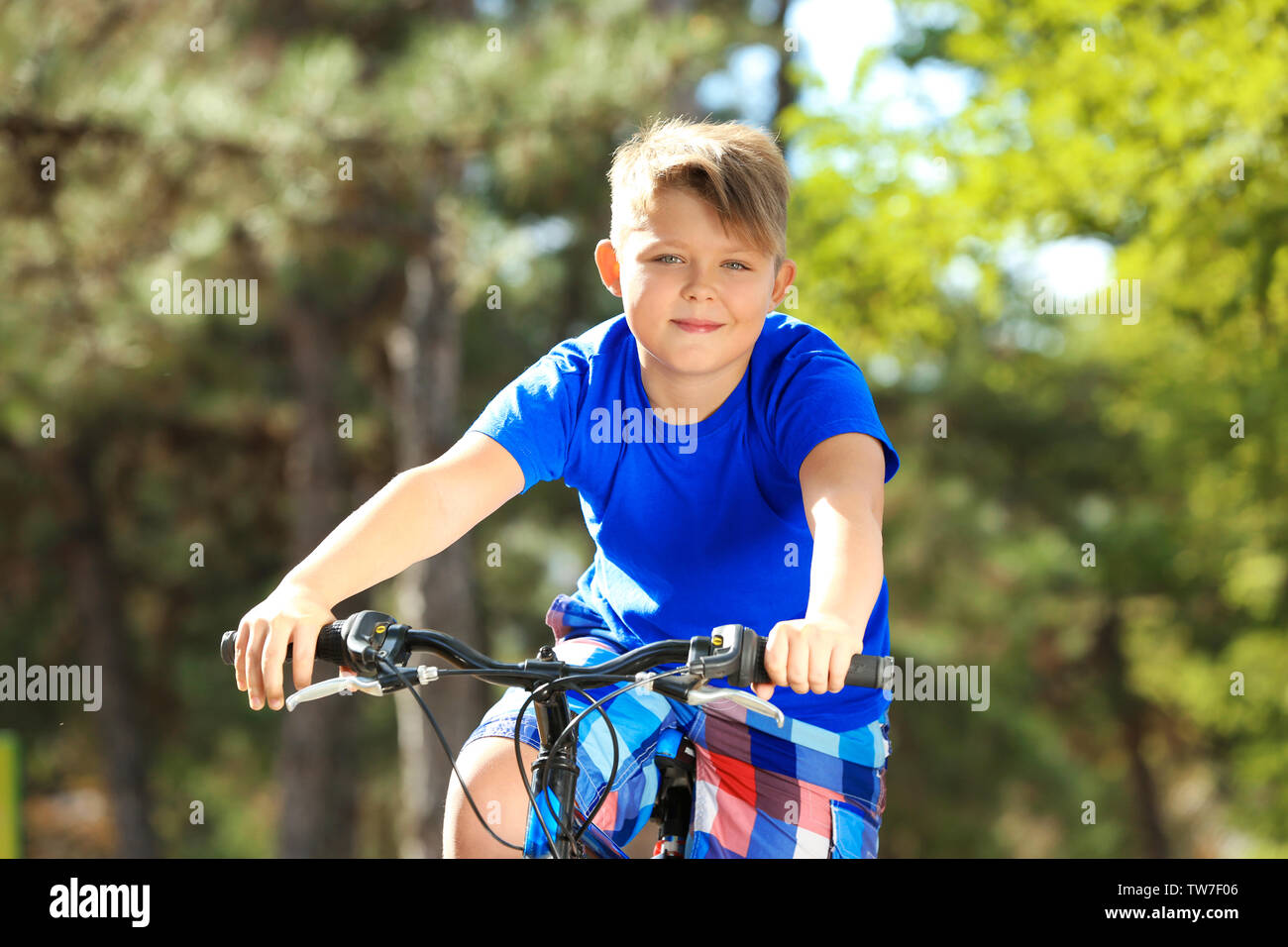 Overweight boy riding bicycle in park Stock Photo Alamy