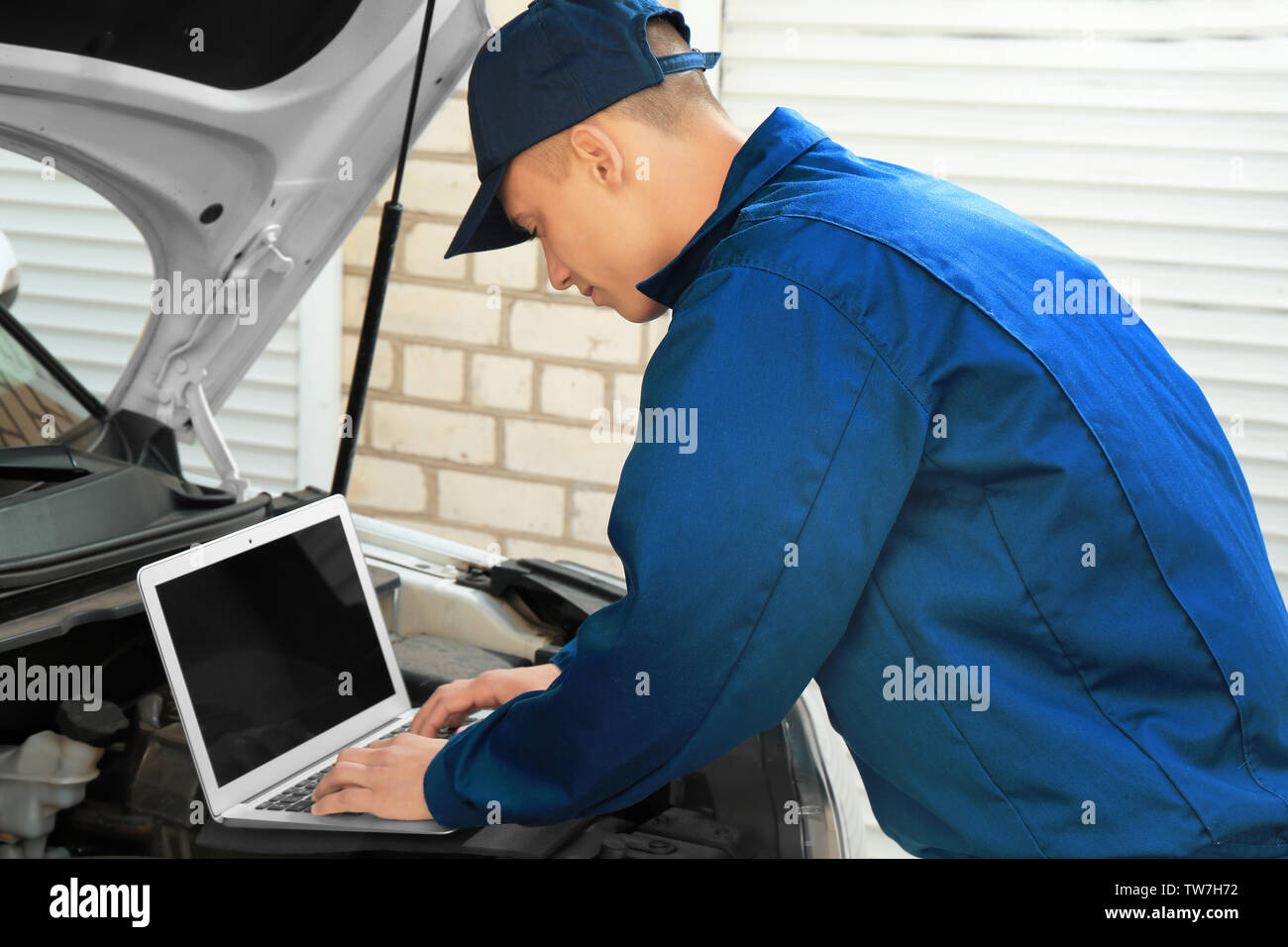 Auto mechanic using computer diagnostic program while repairing car