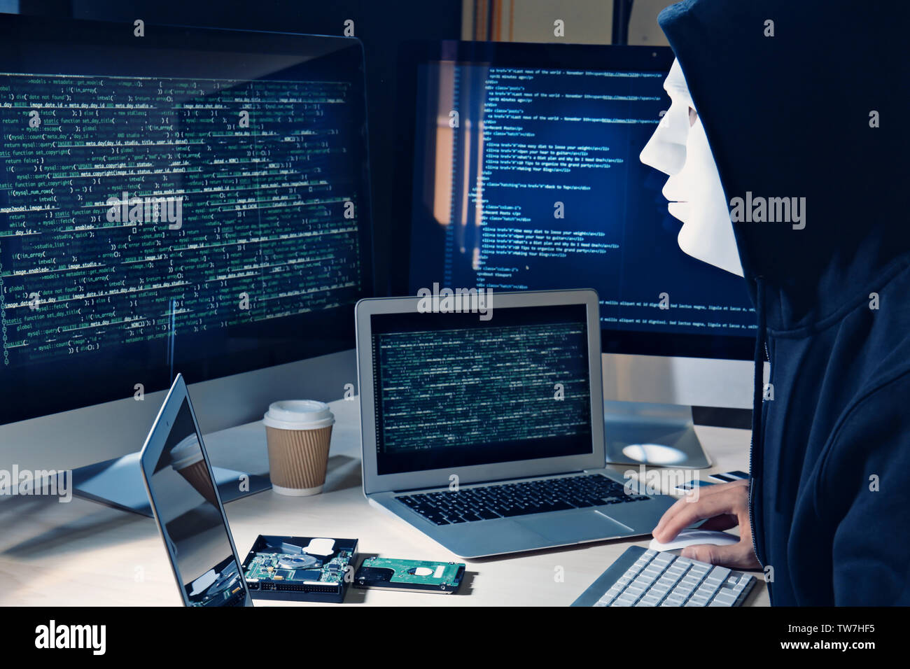 Masked man hacking server in dark room Stock Photo