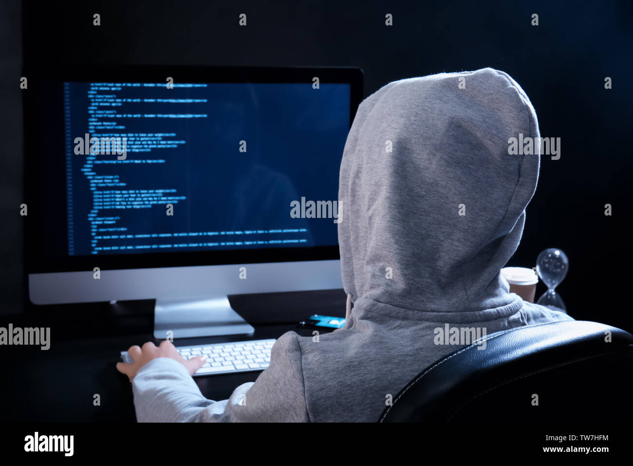 Man wearing hoodie hacking server in dark room Stock Photo - Alamy