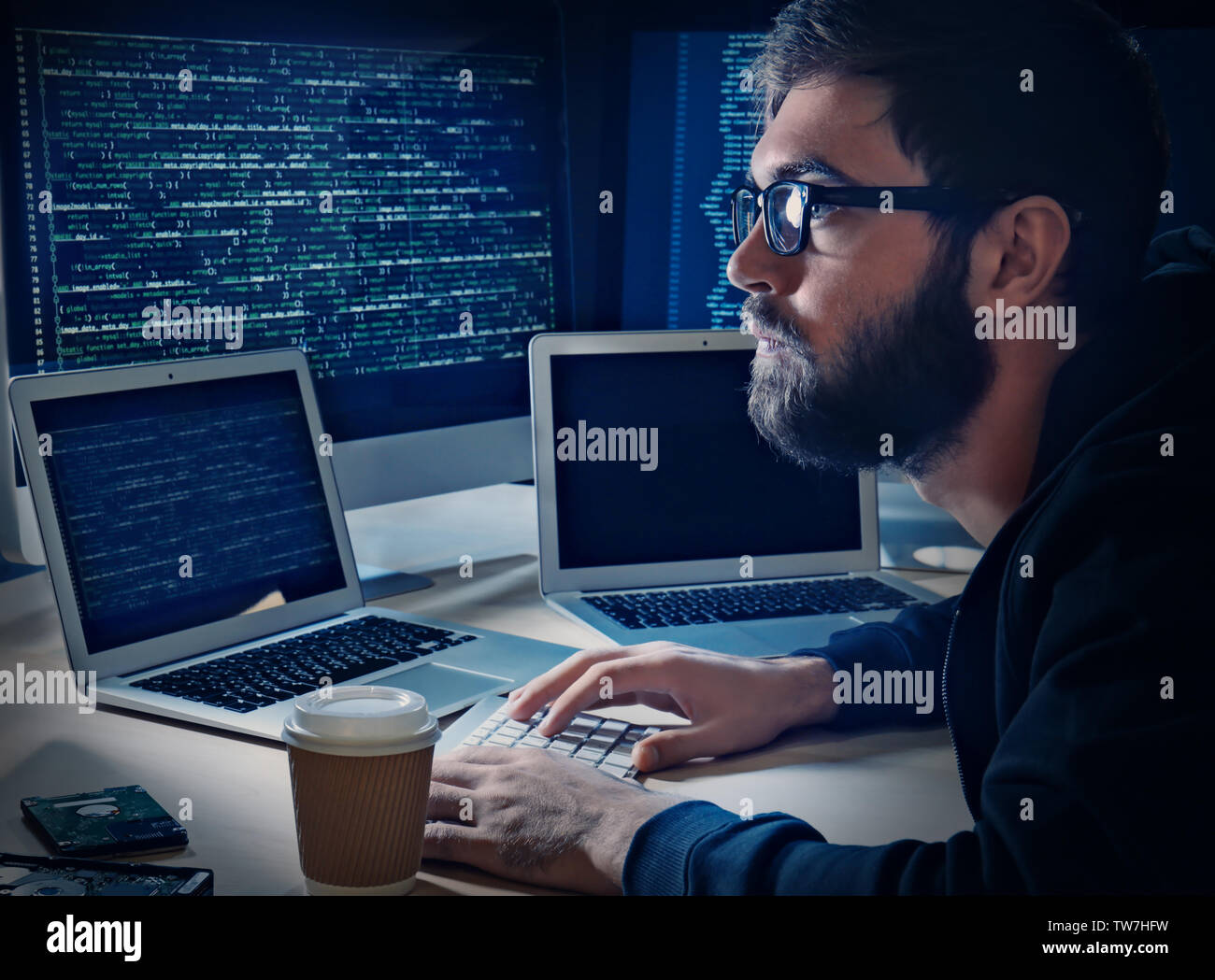 Young man hacking server in dark room Stock Photo