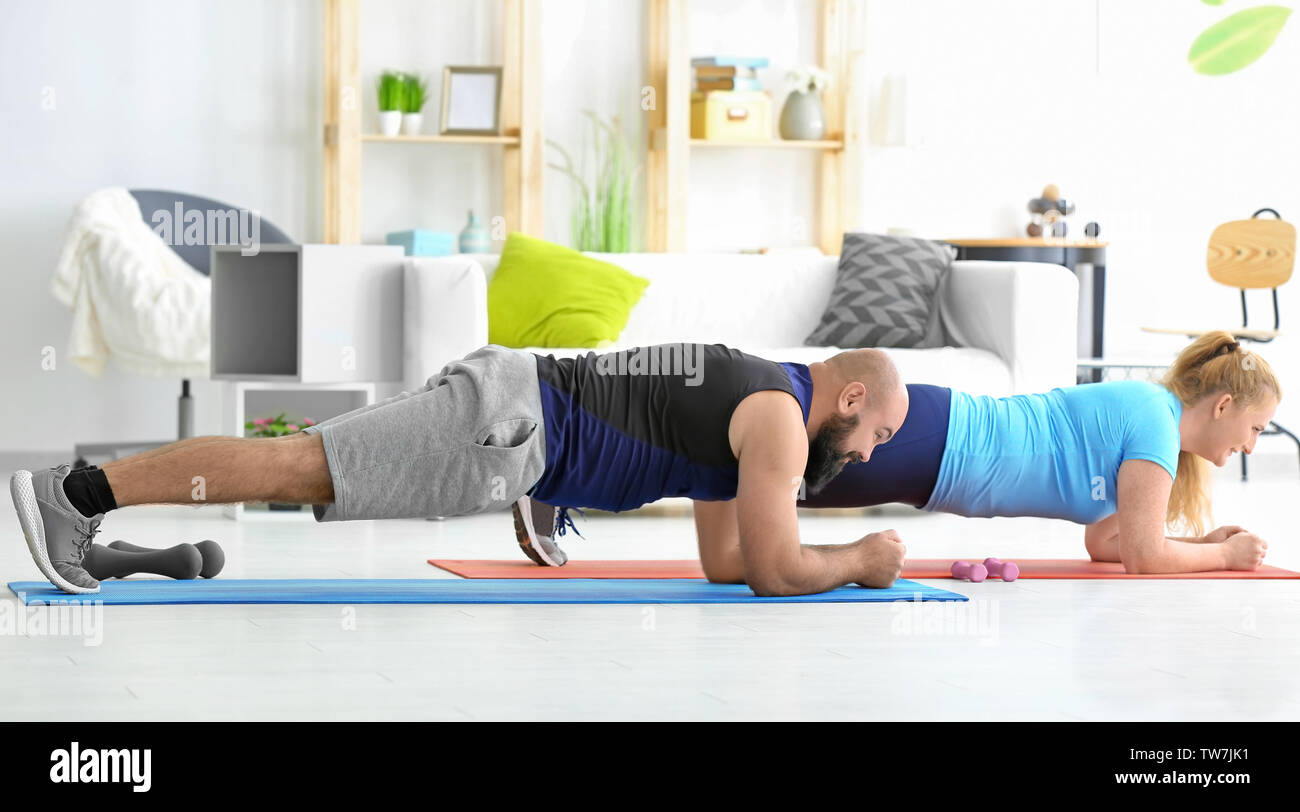 Overweight couple doing exercises at home Stock Photo