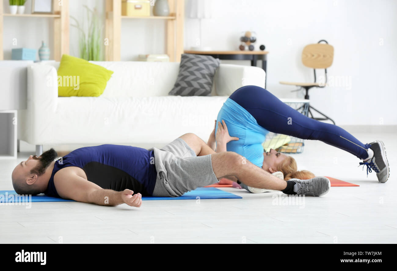 Overweight couple doing exercises at home Stock Photo