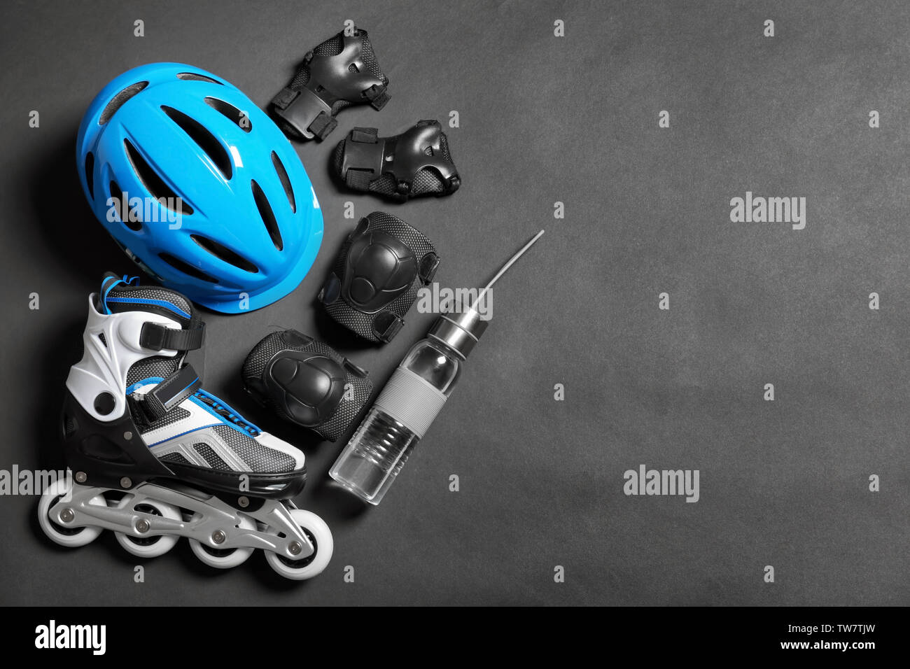 Roller skate, knee pads and bottle of water on grey background Stock