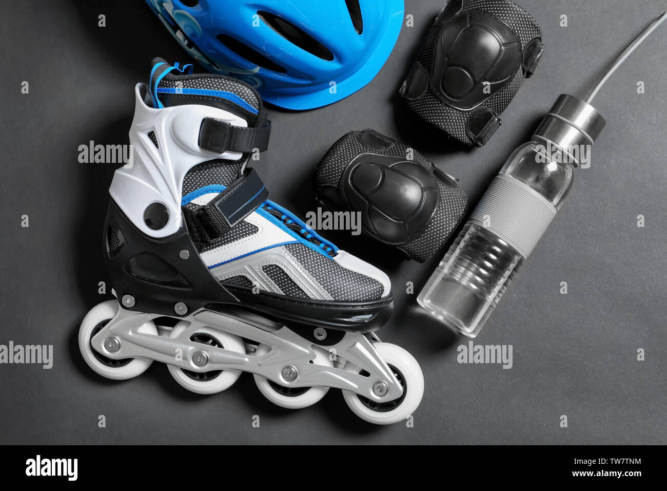 Roller skate, knee pads and bottle of water on grey background Stock