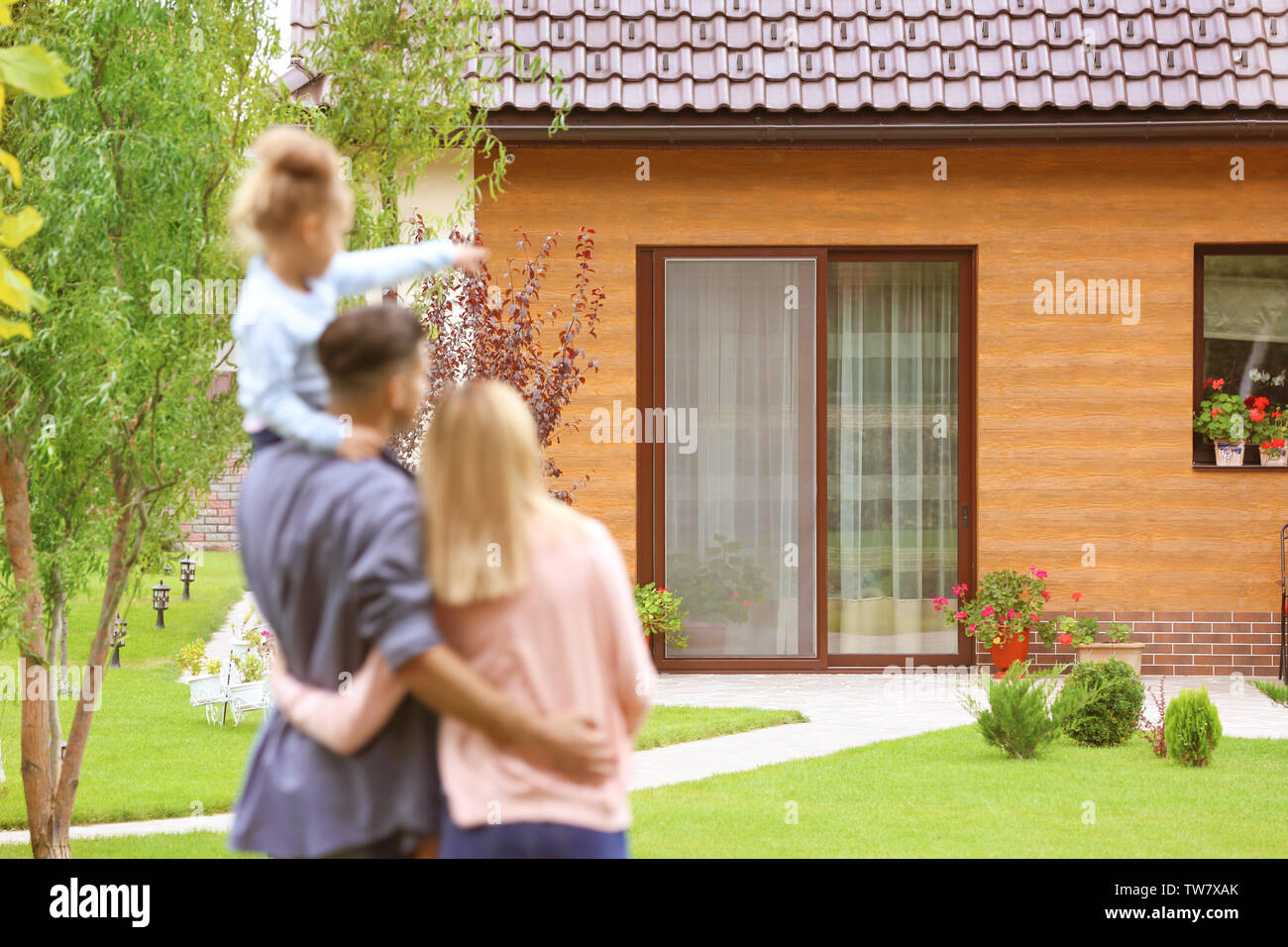 Happy family standing in courtyard and looking at their house Stock Photo