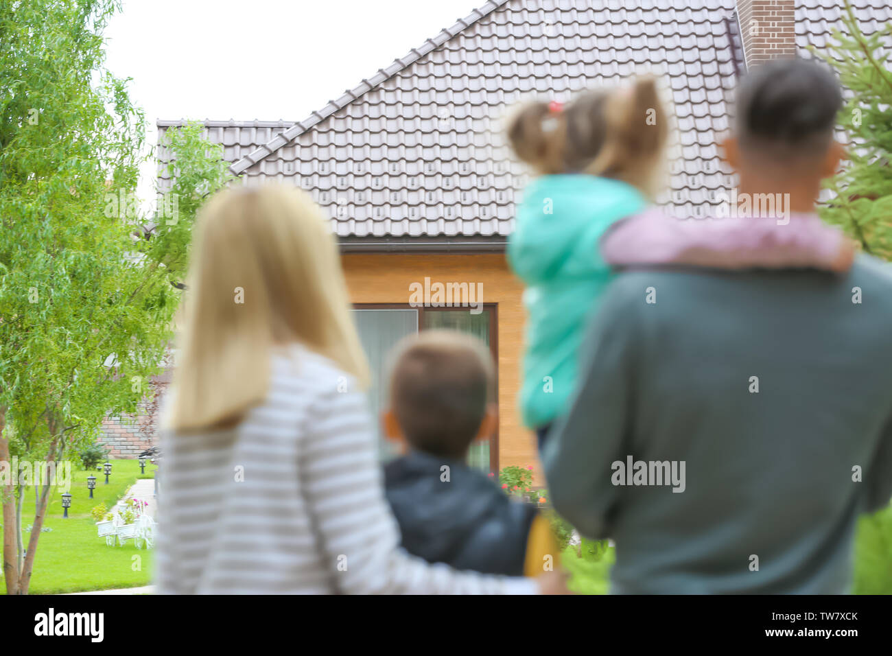 Happy family standing in courtyard and looking at their house Stock Photo